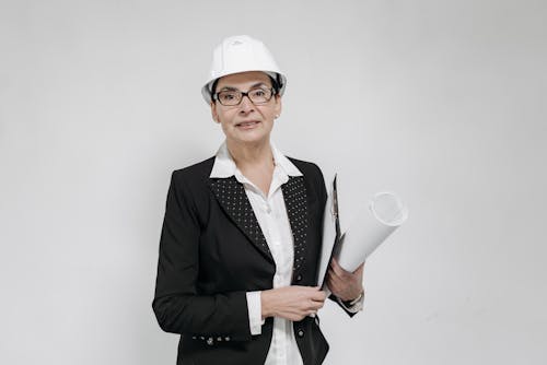 Free Woman in a Suit and White Helmet Holding a Sheet of Paper Stock Photo