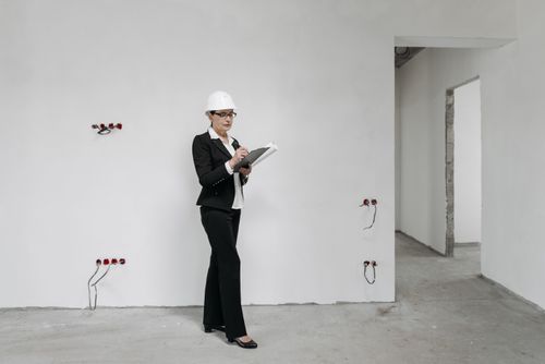 Free Woman in hard hat reviews notes at a construction site, examining progress. Stock Photo