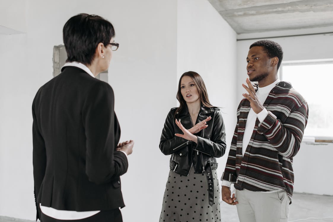 Buying Or Renting A House - Female Realtor Discussing The House Plan With Her Clients Stock Photo