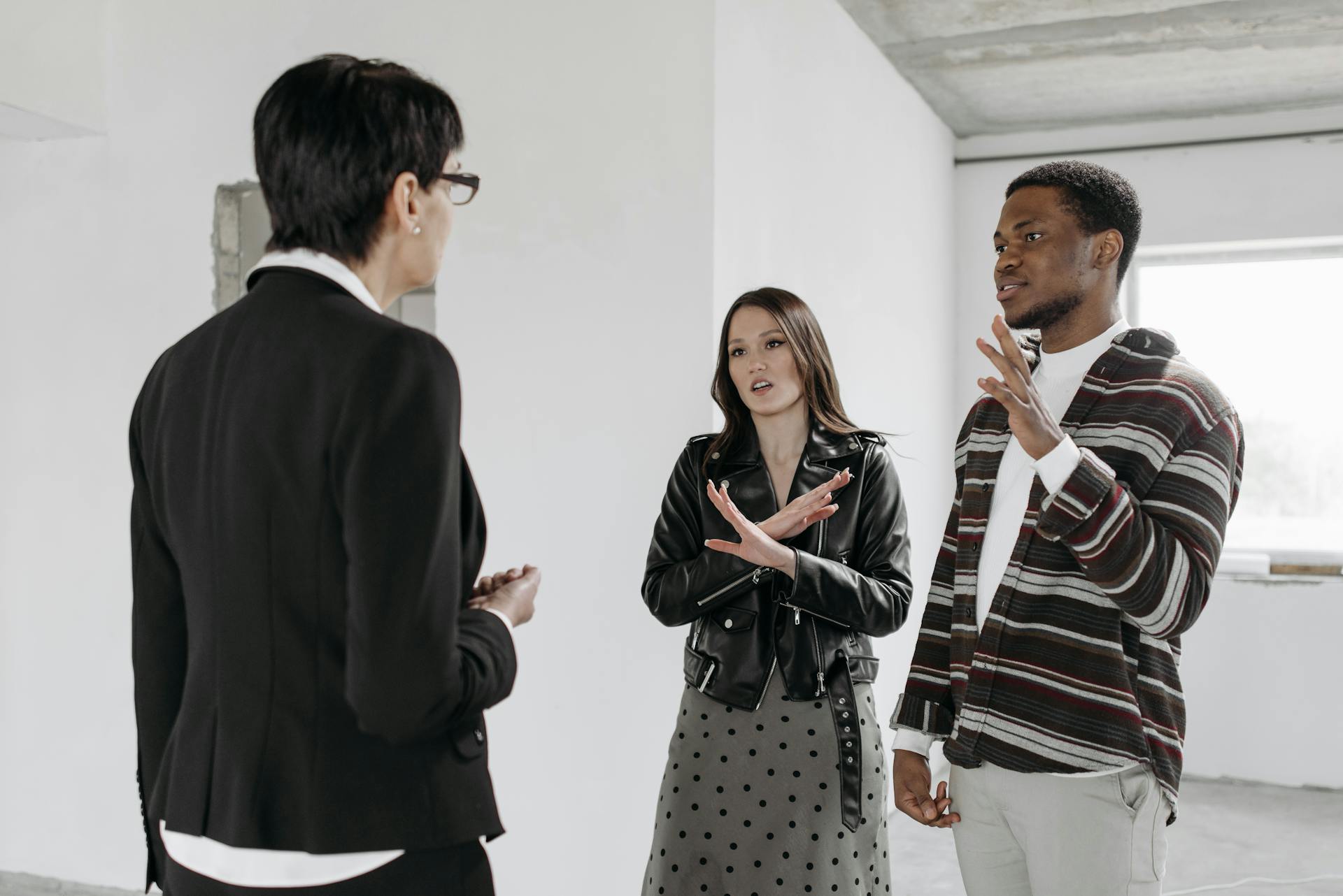 Real estate agents and clients in a conversation about property inside a modern space.