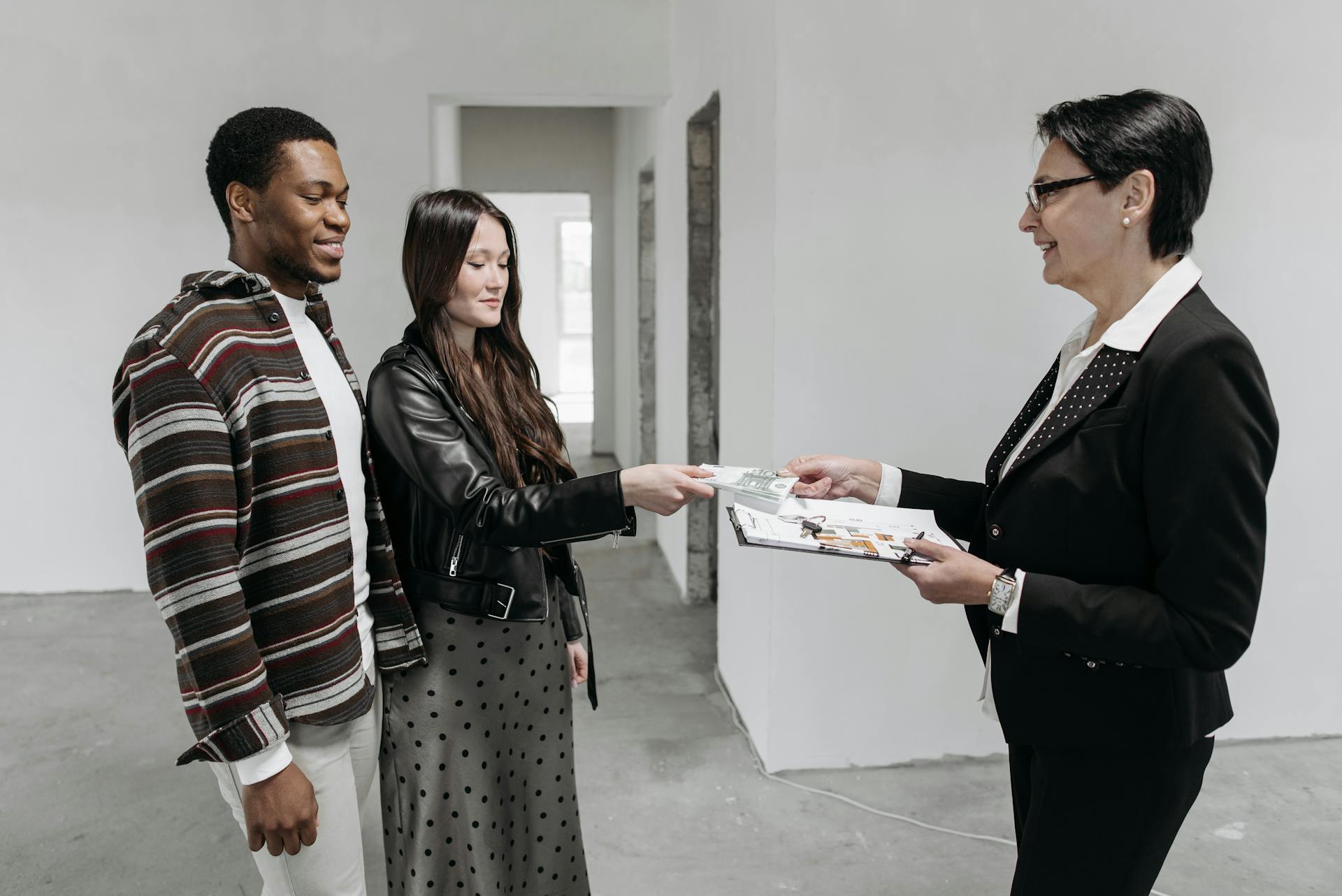 A couple finalizes a home purchase with a real estate agent indoors.