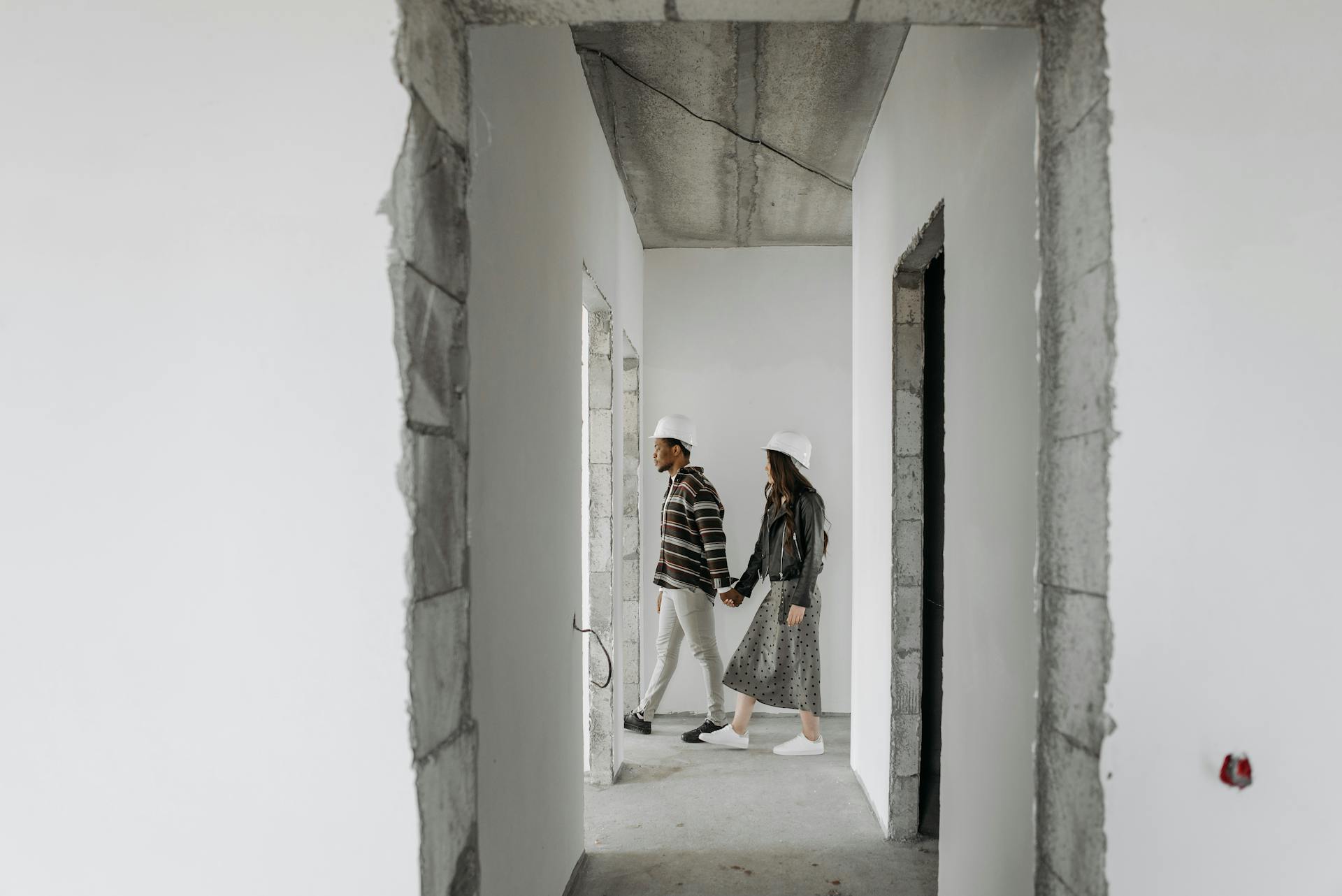 A Couple Wearing Hard Hat Touring Inside the Unfinished House