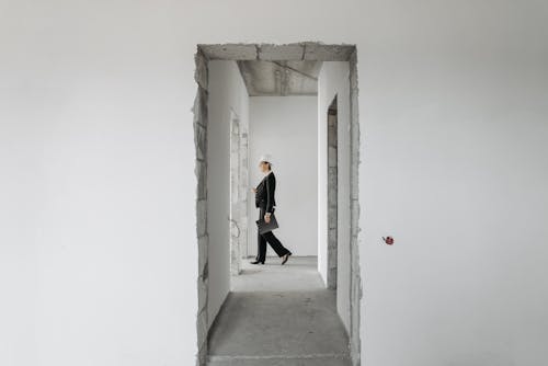 A Woman Wearing Formal Attire Walking Inside an Unfinished House