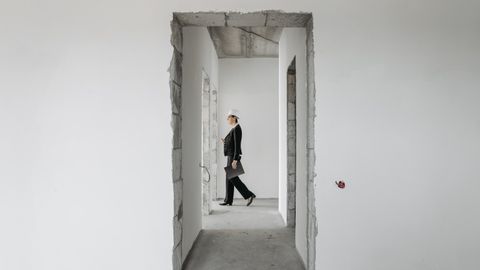 Professional woman in formal attire inspects an unfinished construction site. Ideal for real estate and construction themes.