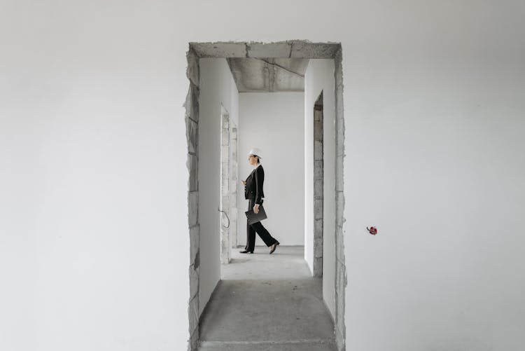 A Woman Wearing Formal Attire Walking Inside An Unfinished House