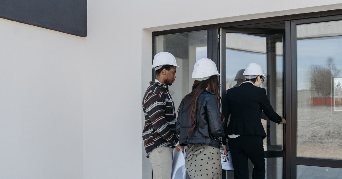 A group of diverse clients with a realtor at a new construction site entrance.
