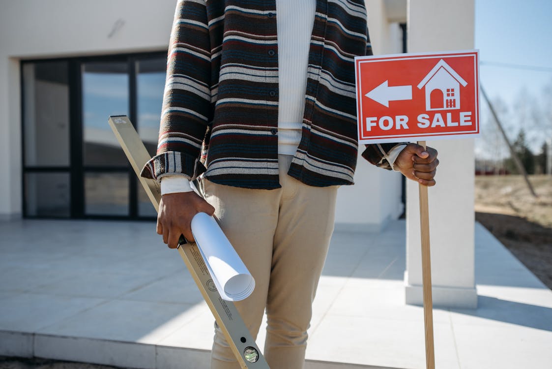 Realtor holding a “for sale” sign