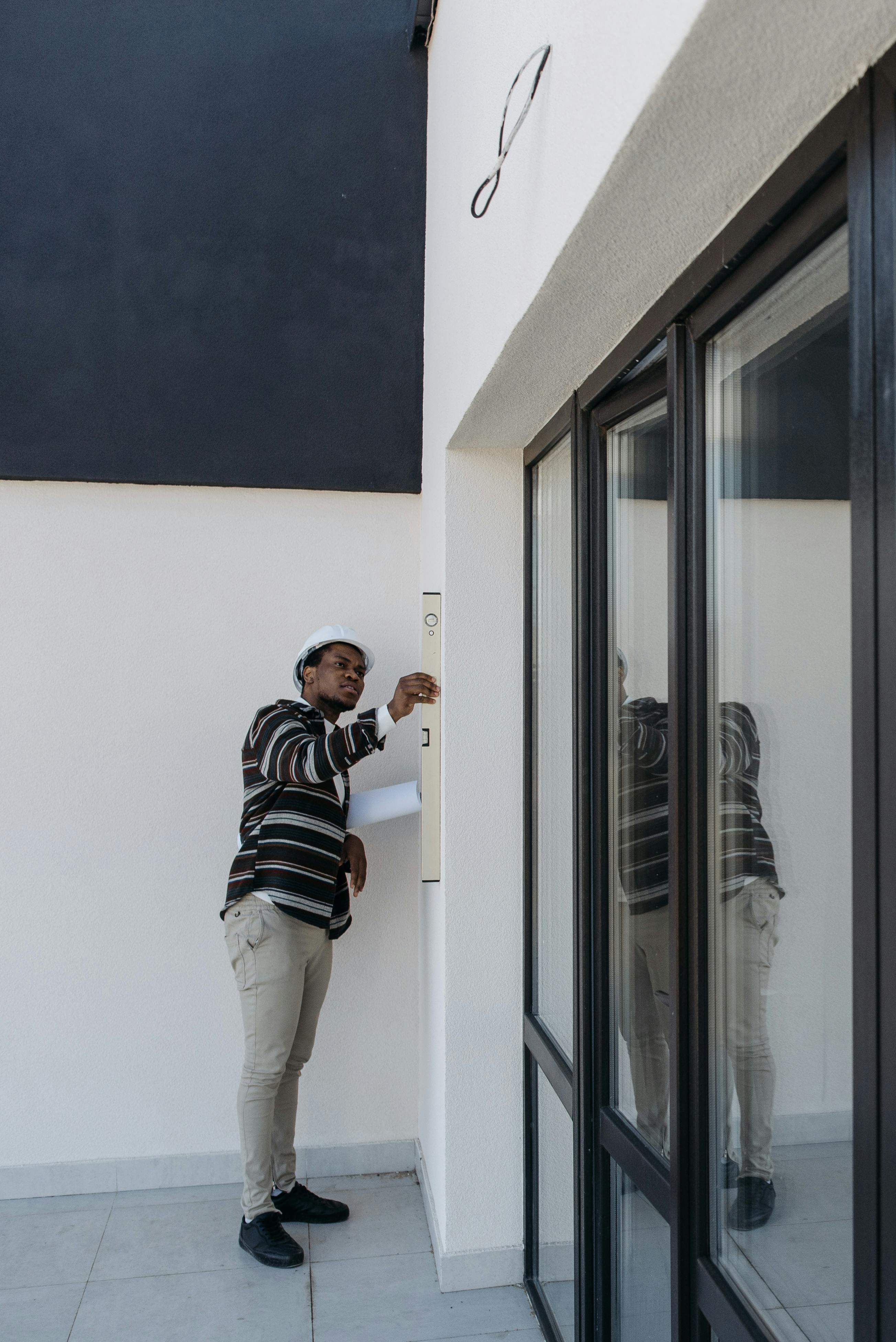 a man wearing hard hat checking the walls of a house