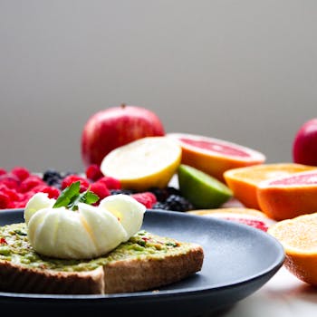 Delicious avocado toast topped with a poached egg and surrounded by fresh fruits, ideal for a healthy lifestyle.