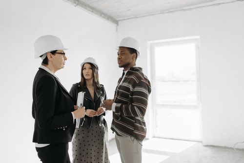 Free Three professionals in safety helmets discuss a construction project. Stock Photo