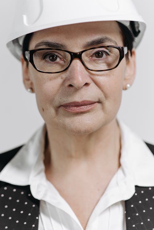 A Close-up Shot of a Woman Wearing an Eyeglasses and a Hard Hat