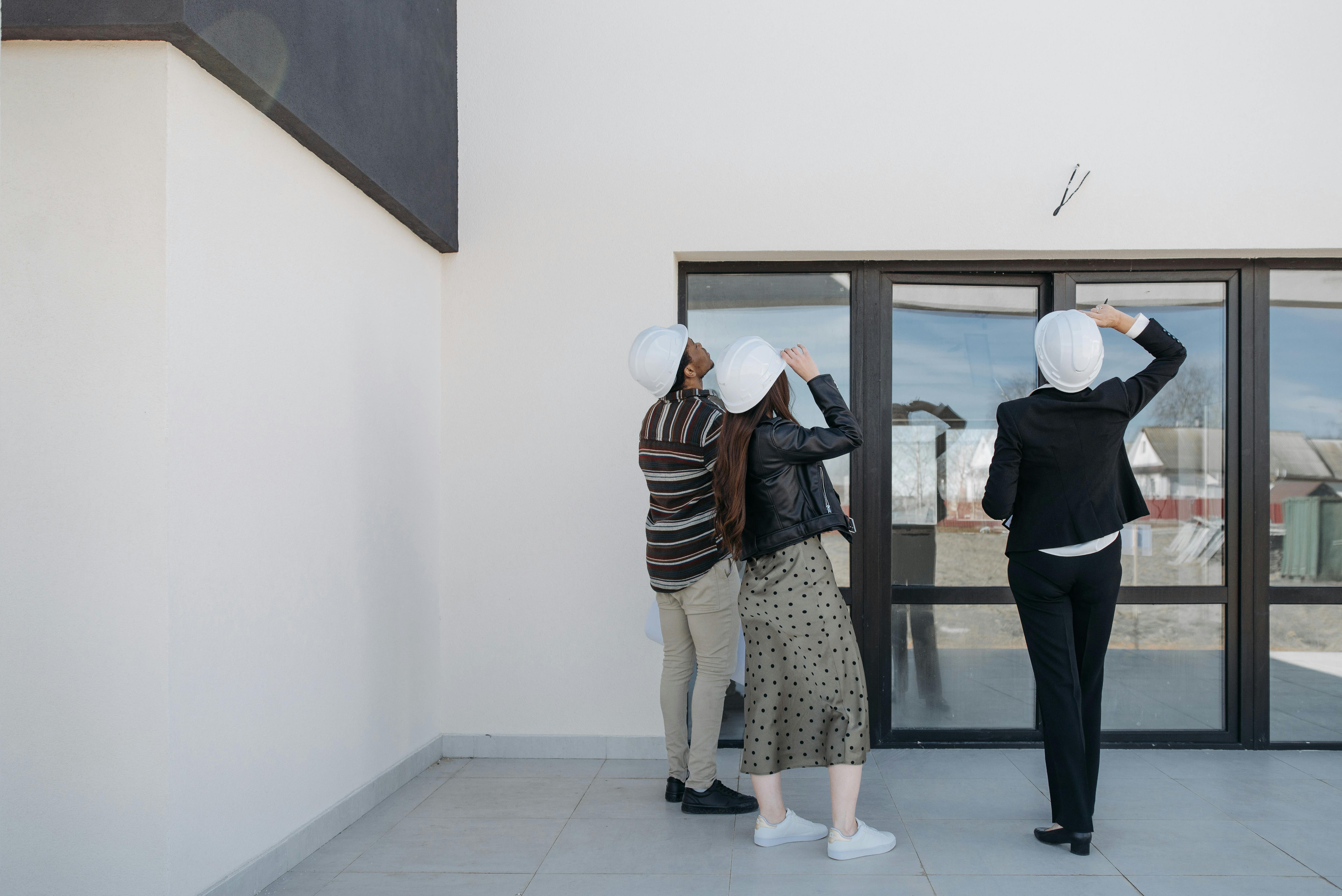 Free Real Estate Agent and Clients Looking at House for Sale Stock Photo