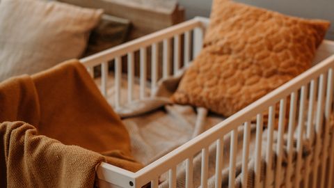 A warm, inviting nursery displaying a stylish crib adorned with textured pillows and a plush blanket.