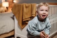 Boy in Gray Long Sleeve Shirt Sitting on Brown Couch