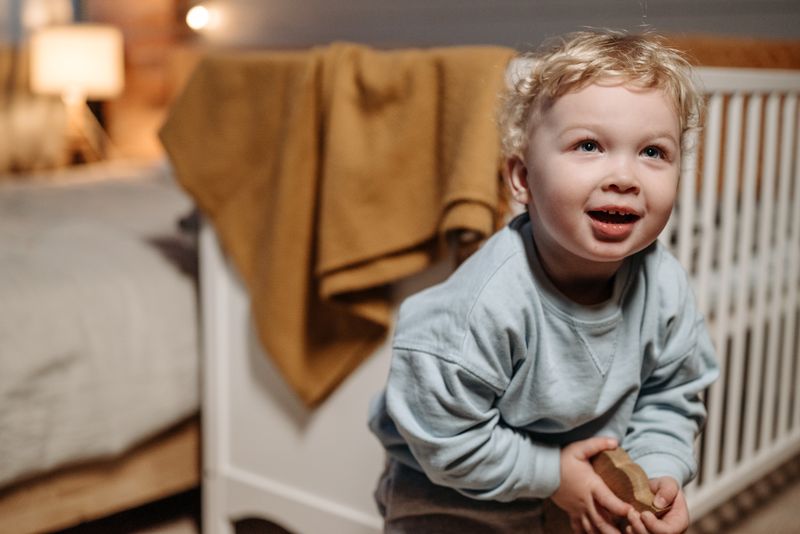 Niño rubio jugando con un juguete de madera en una habitación acogedora