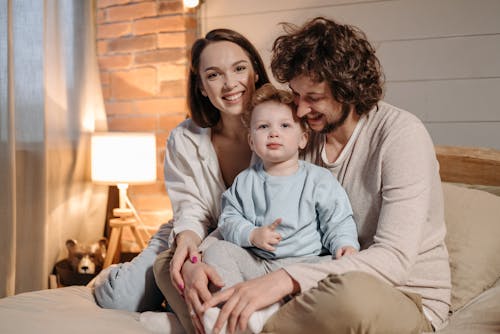 Free A Happy Family Sitting on the Bed Stock Photo