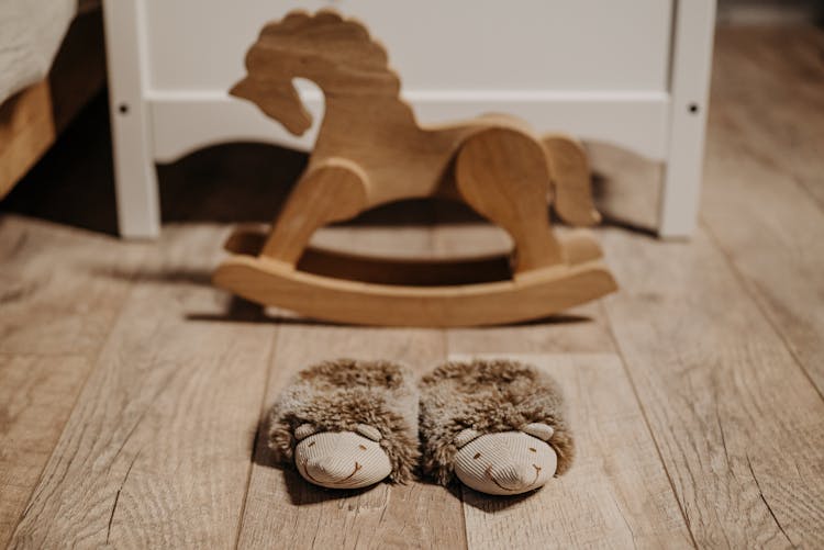 Brown Furry Slippers And A Wooden Rocking Horse On The Floor