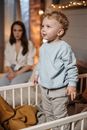 Boy in Blue Sweater Standing Beside Brown Wooden Crib