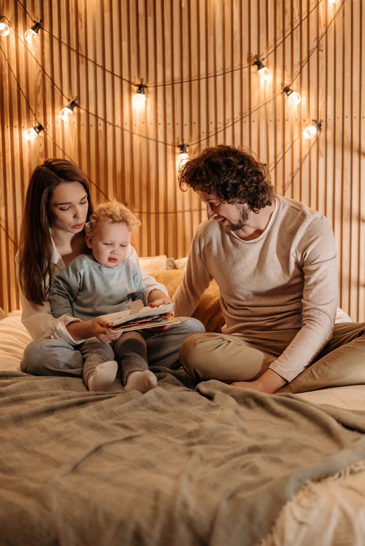 Parents Sitting On The Bed With Their Baby