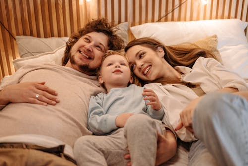Free A Happy Family Lying Down on the Bed Stock Photo