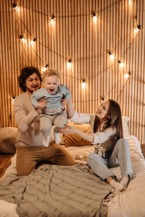 Free A Happy Family Having Fun Playing Together on a Bed Stock Photo