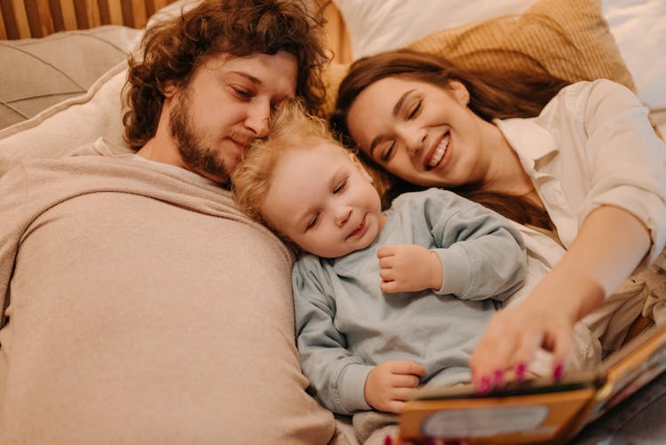 Parents Reading A Bedtime Story For Their Daughter