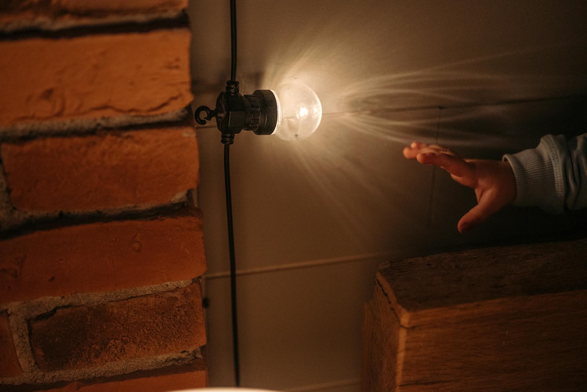 Childs Hand Reaching for Light Bulb