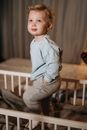 Boy in Blue Dress Shirt and Gray Pants Standing on Brown Wooden Crib