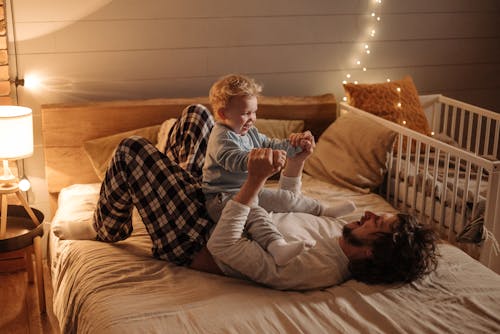 Free Father and Child Playing on Bed Stock Photo