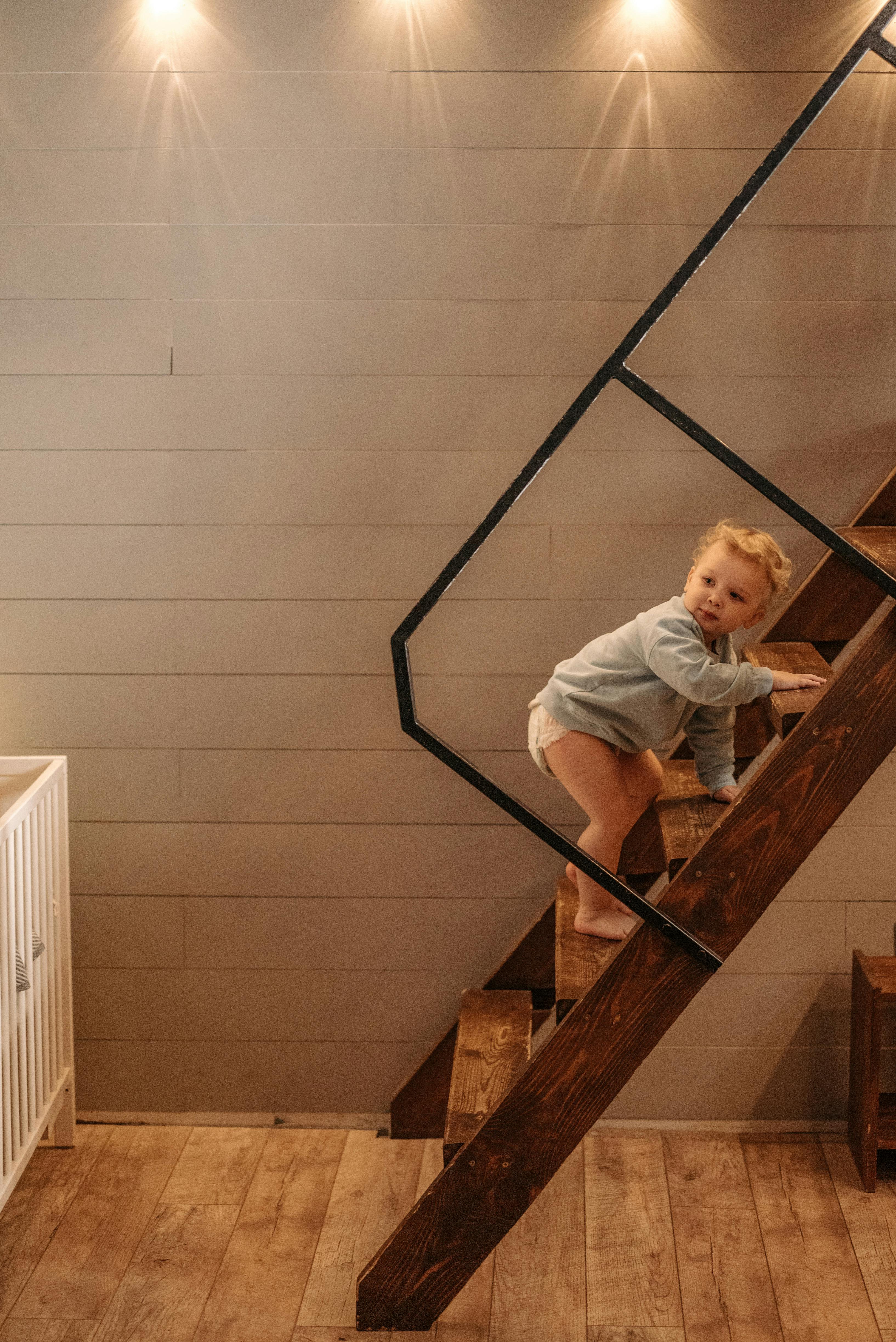 a toddler climbing on brown wooden staircase