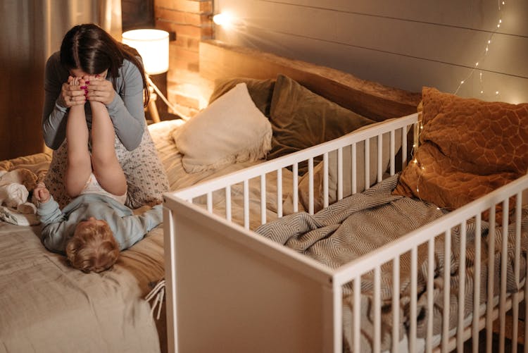 Mother And Child Playing While On The Bed