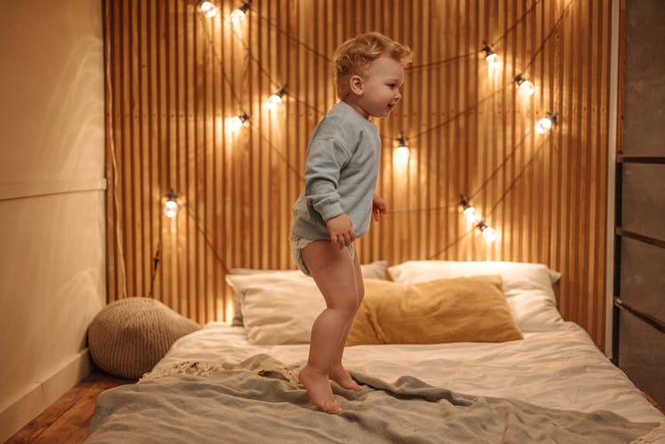 A Toddler Jumping On Bed