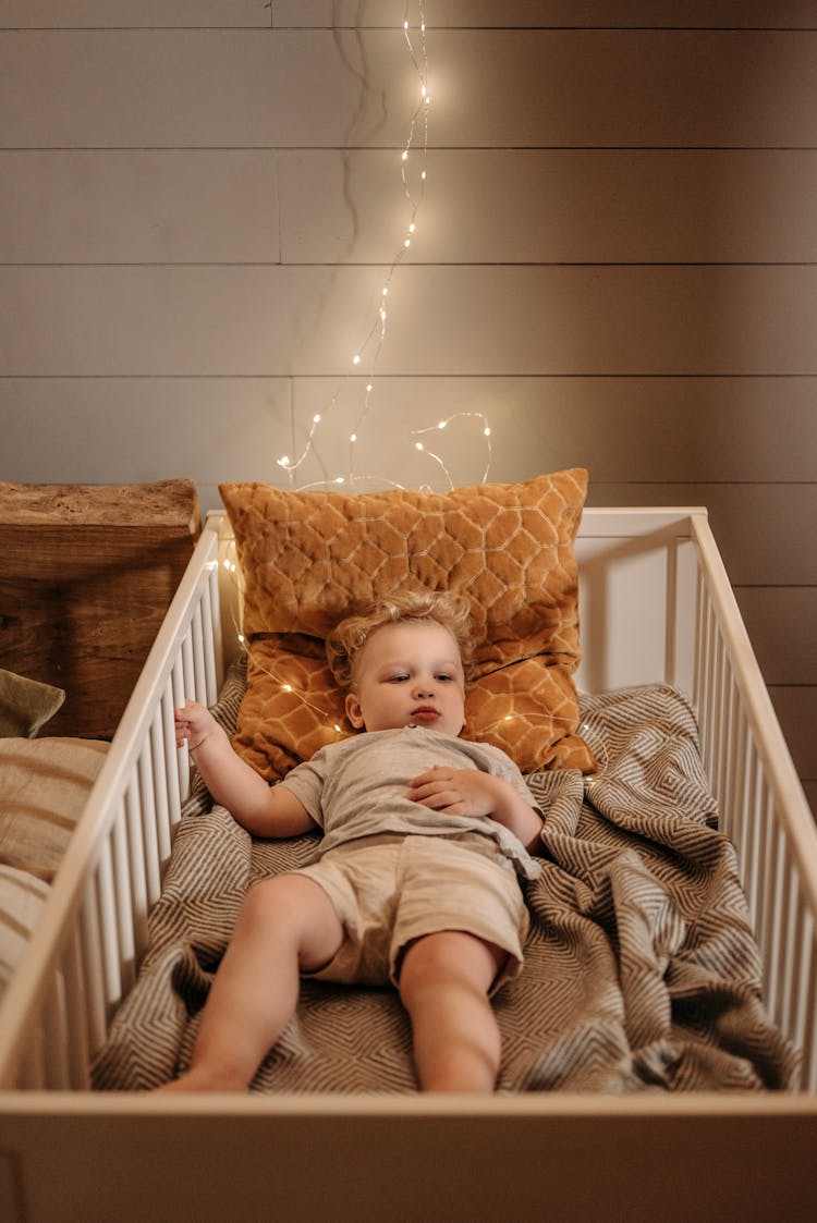 A Young Boy Lying On The Crib