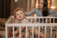 A Woman Watching Over His Son on the Wooden Crib