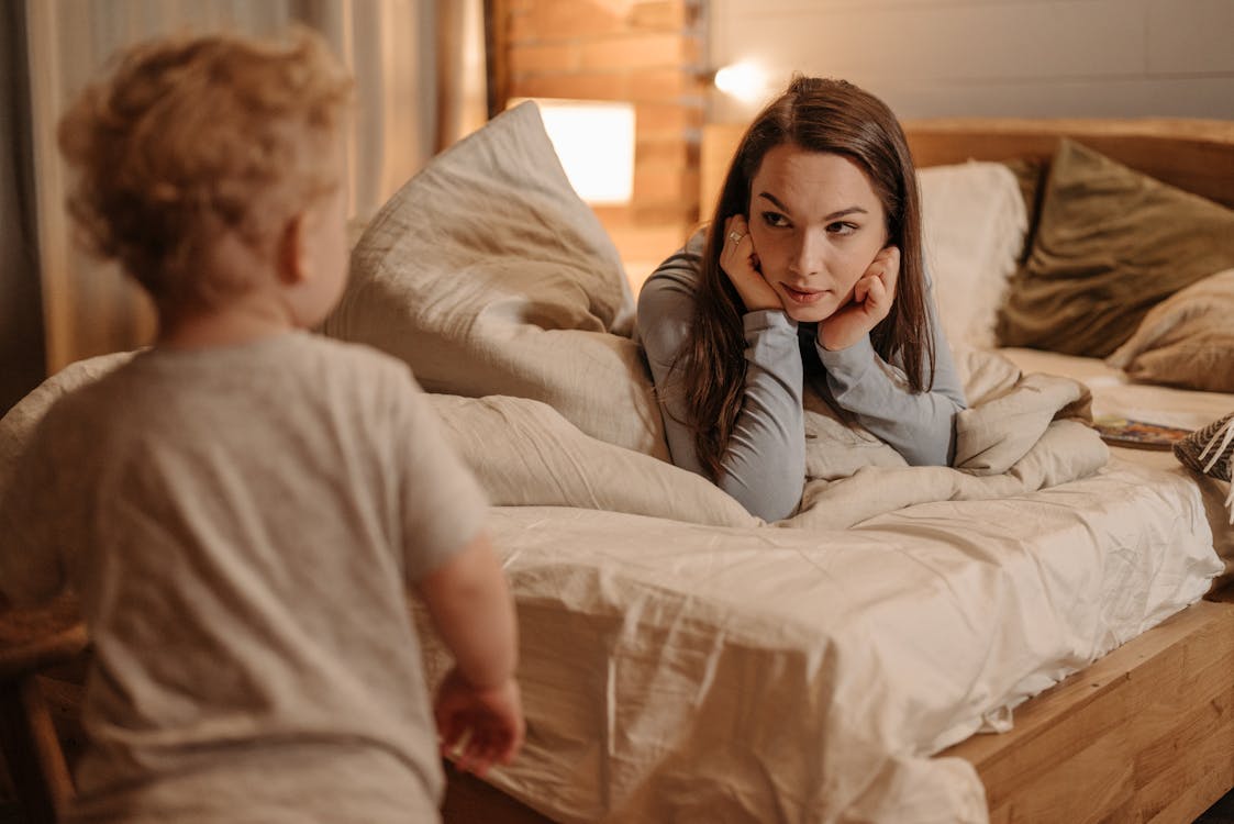 Free Little Boy Looking at Mother Lying on Bed Stock Photo