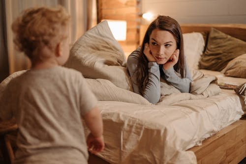 Free Little Boy Looking at Mother Lying on Bed Stock Photo