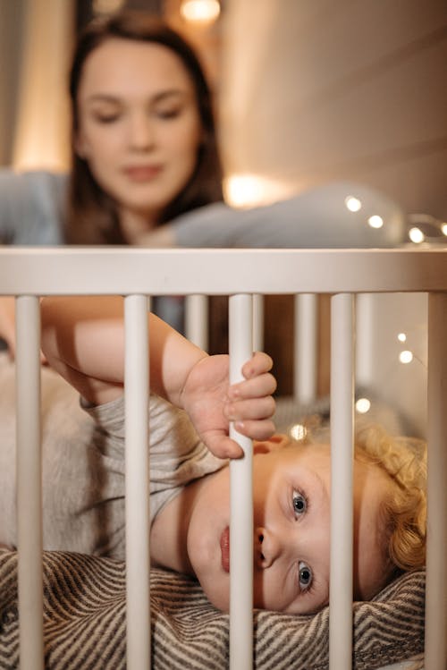 Free A Woman Looking at Her Baby Lying on the Crib Stock Photo