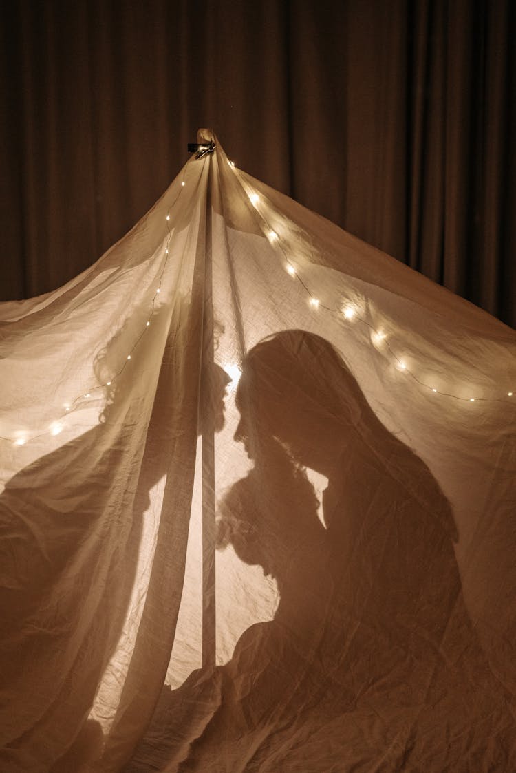 A Family Inside A Blanket Tent With White String Lights