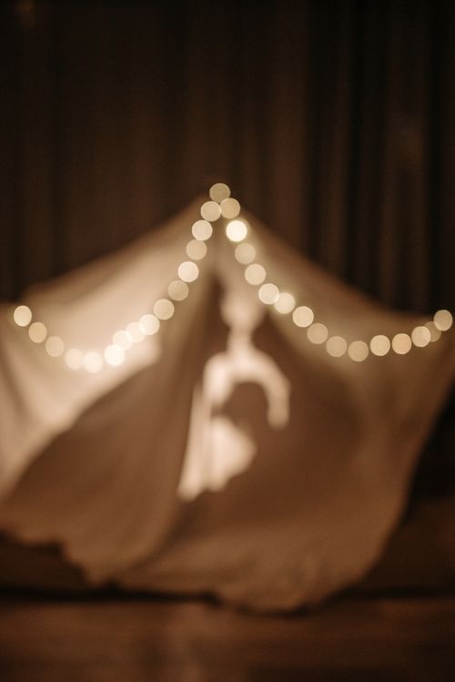 Free A defocused silhouette inside a tent draped with warm fairy lights, creating a cozy and magical atmosphere. Stock Photo
