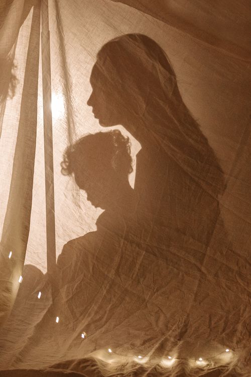 Free Warm silhouette of mother and child behind linen curtain, embracing love. Stock Photo
