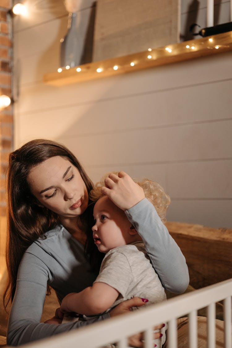 Woman In Gray Long Sleeve Shirt Cuddling A Baby