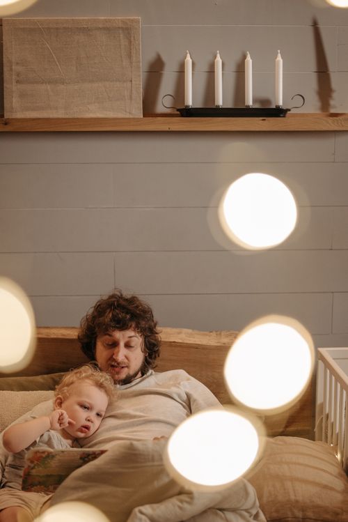 Free A father and son share a bonding bedtime story in a warmly lit bedroom. Stock Photo