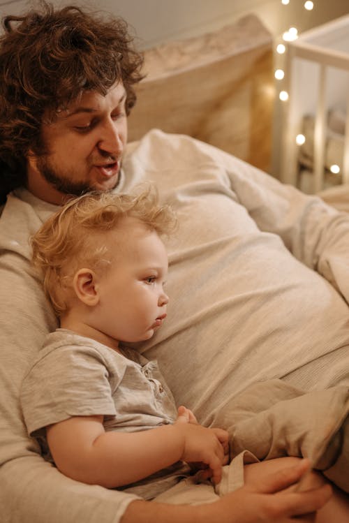 Free Man in Gray Shirt Lying on Bed Beside a Baby Stock Photo