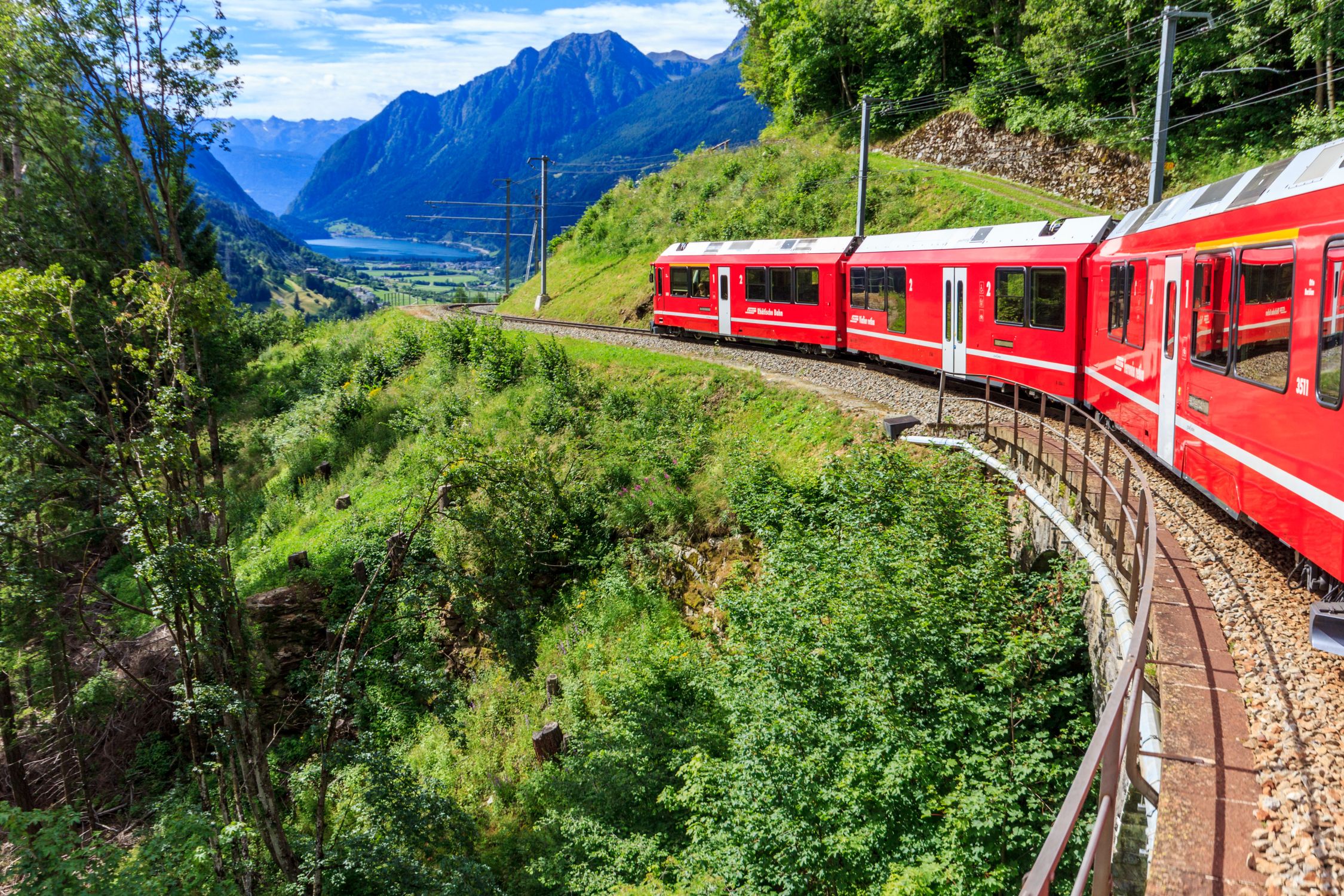 Bernina Express train curves through the stunning Swiss Alps, offering breathtaking views of mountains and valleys.