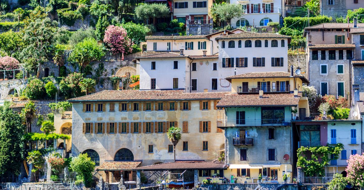 Scenic view of hillside Italian village, colorful houses by Lake Lugano.