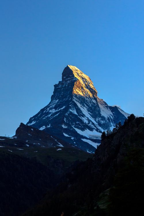 Free Stunning view of the Matterhorn peak illuminated by sunset light against a clear blue sky. Stock Photo