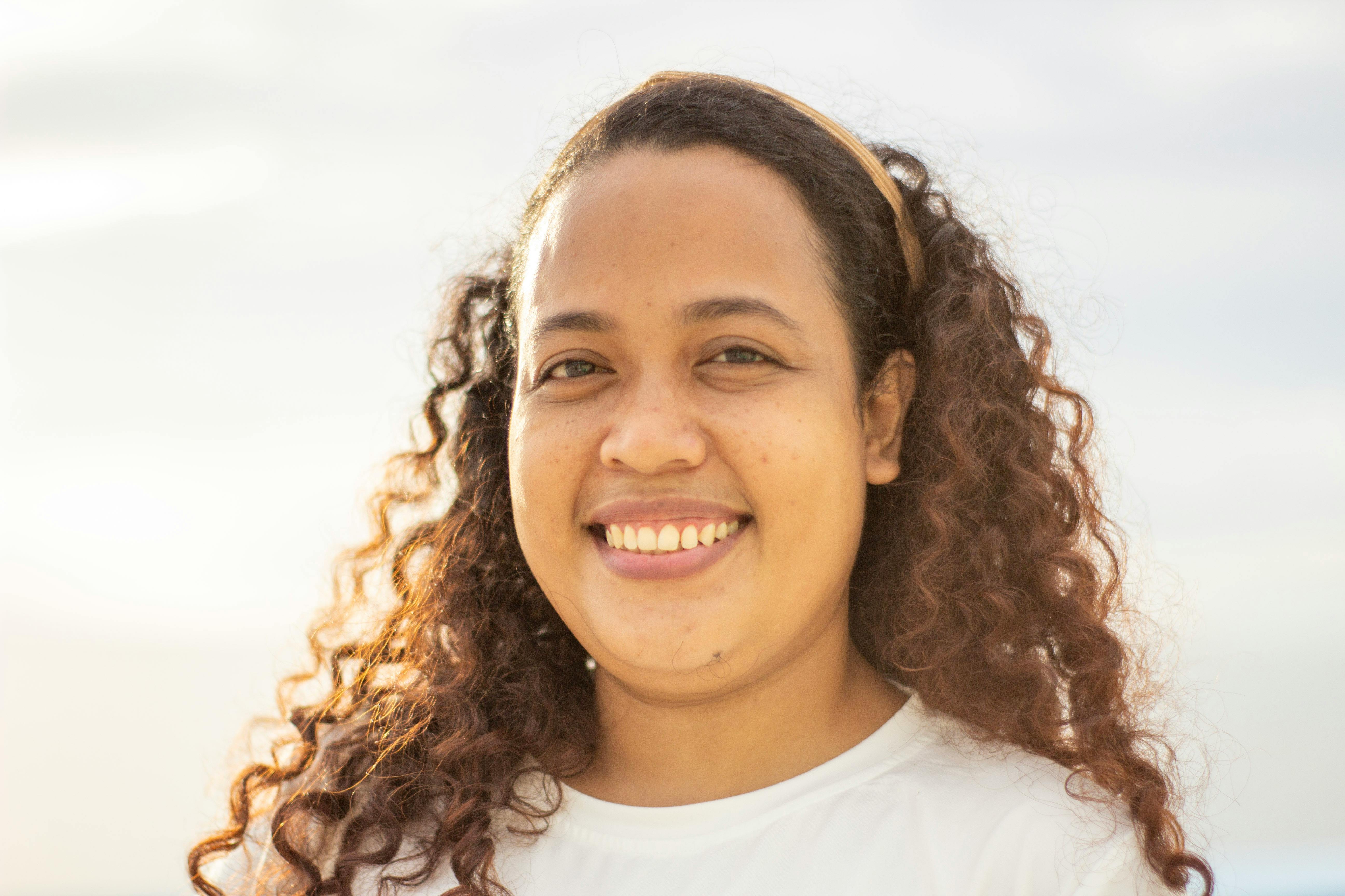 Portrait of a joyful woman with curly hair enjoying a sunny day outdoors.