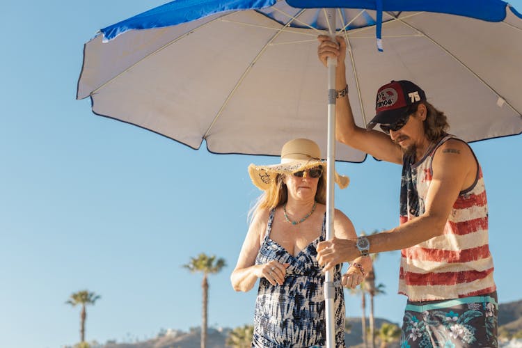 Man And Woman Standing Under The Beach Umbrella