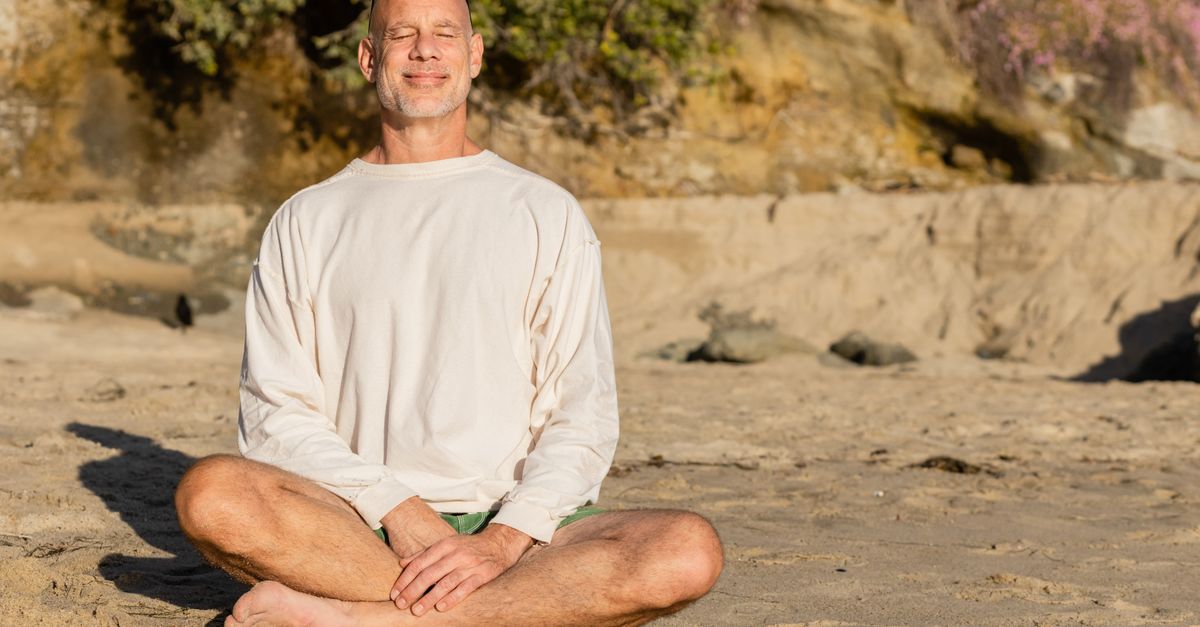 person sitting cross-legged in sunlight, smiling peacefully with eyes closed