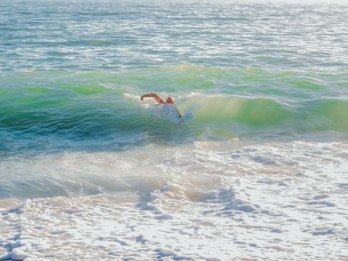 Free An elderly man swimming in vibrant ocean waves under bright sunlight, reflecting a healthy lifestyle. Stock Photo